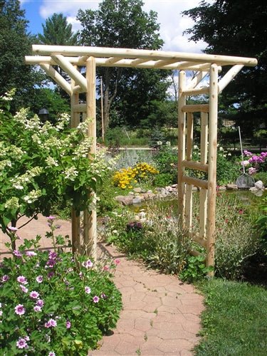 A rustic wooden garden bridge in a lush backyard, surrounded by vibrant flowers, greenery, and a peaceful landscape.
