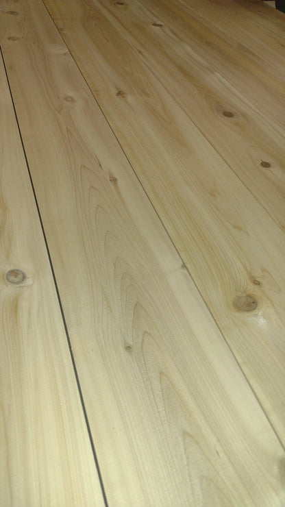 Detailed view of the tabletop surface on an outdoor farmhouse patio table, showing smooth planks and visible knots.